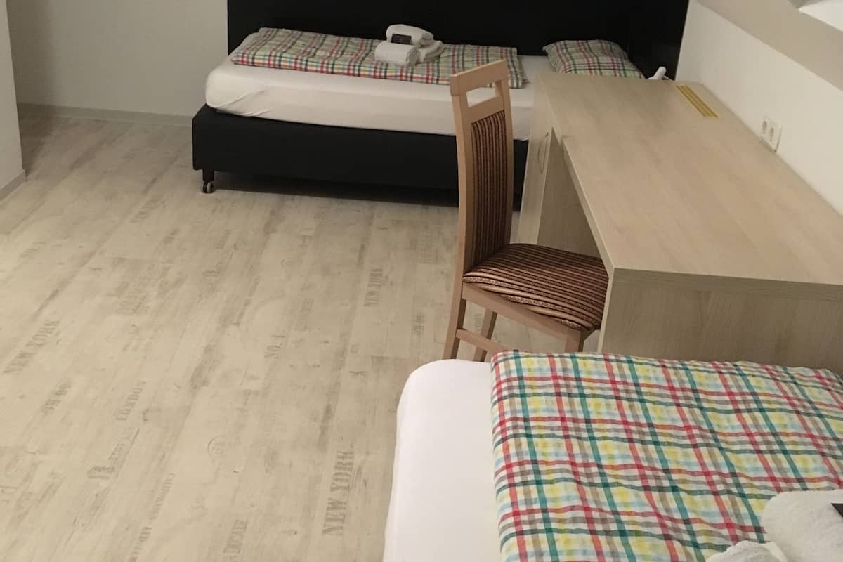 A bedroom with two beds, a wooden chair, and a desk.