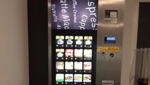 A coffee vending machine with various drink options displayed on a digital screen. - Penny-Pension (Gross Twulpstedt)