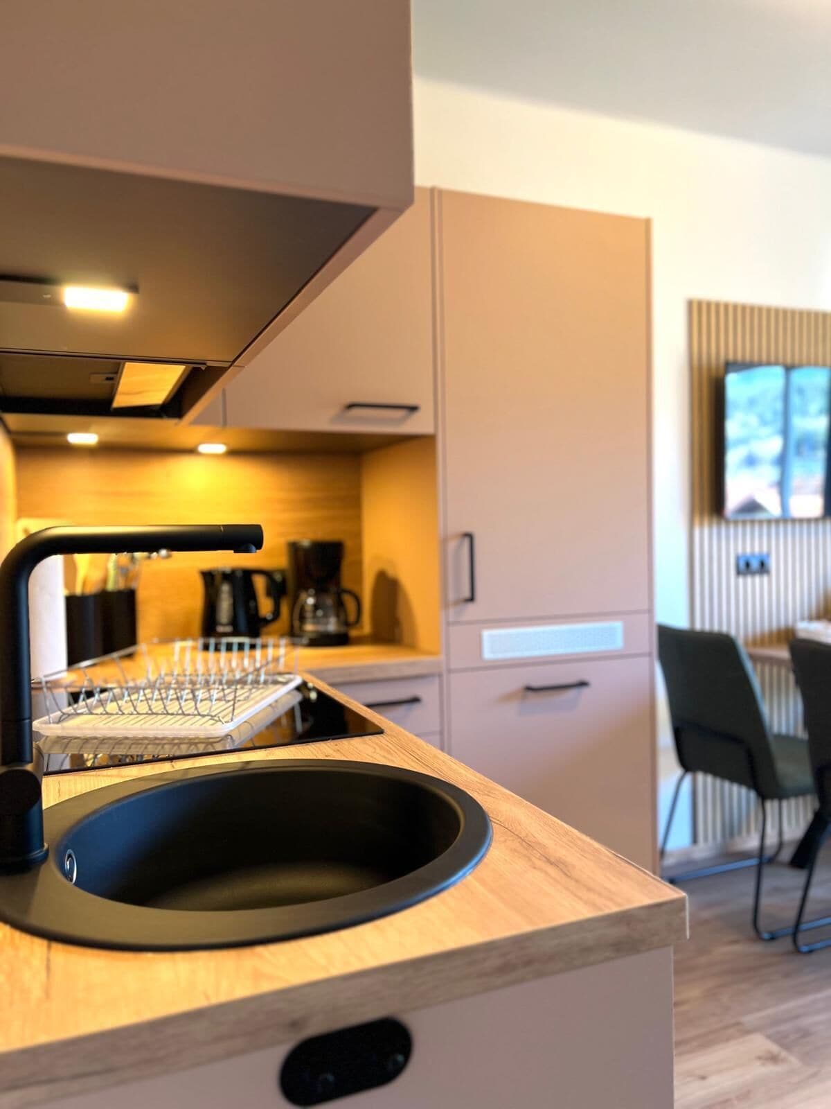 Une cuisine moderne dotée d’un évier encastré, d’une machine à café et d’un coin repas avec des chaises.