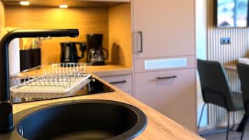 Una cocina moderna con pileta integrada, cafetera y comedor con sillas.