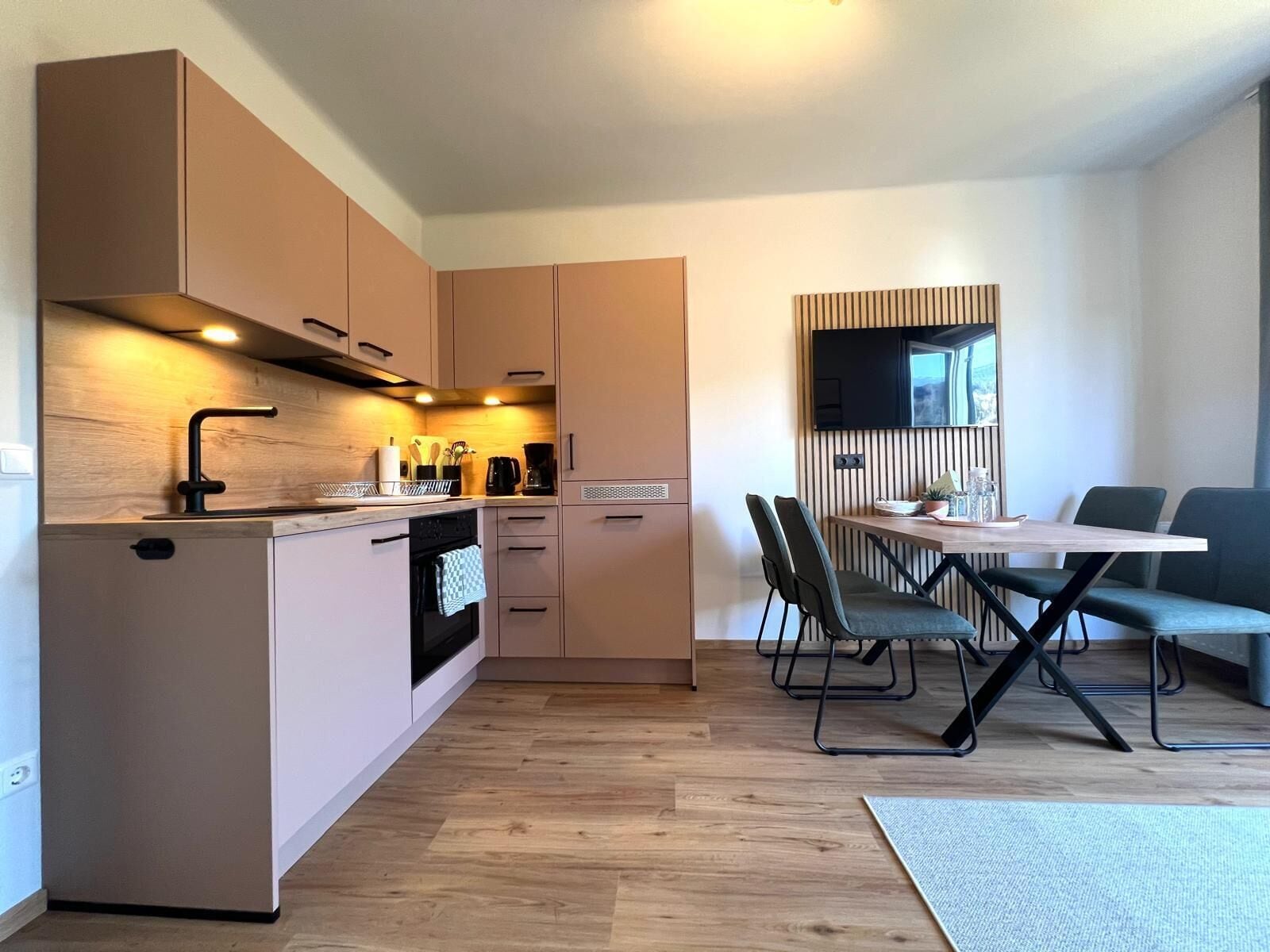 Uma cozinha moderna com armários de madeira, forno embutido e uma área de jantar com mesa e cadeiras.