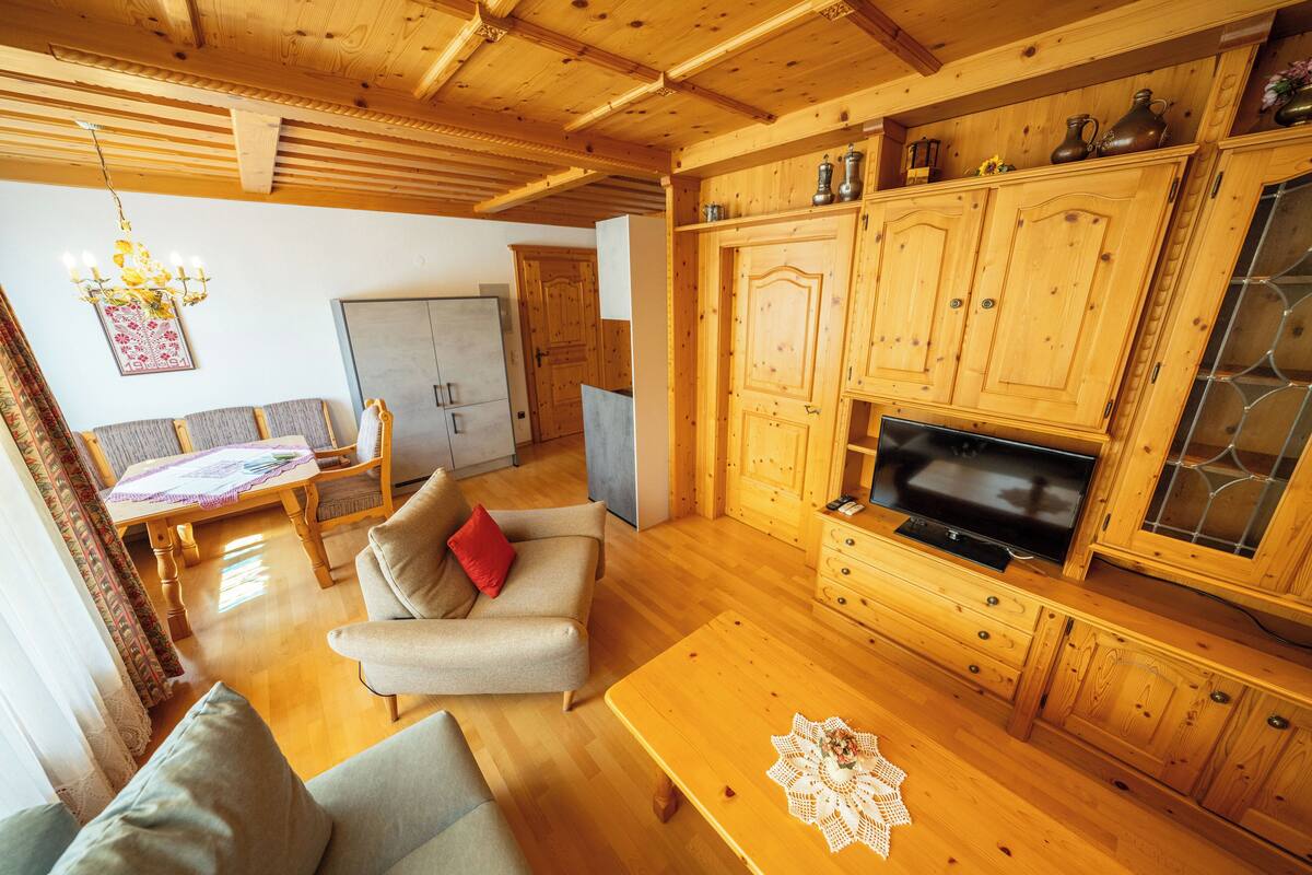 Ein Wohnzimmer mit Holzboden, einer Couch, einem Couchtisch und einem Fernseher.