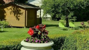 Ein Garten mit einem großen Pflanzgefäß, einem Gebäude und einem Stuhl im Hintergrund.