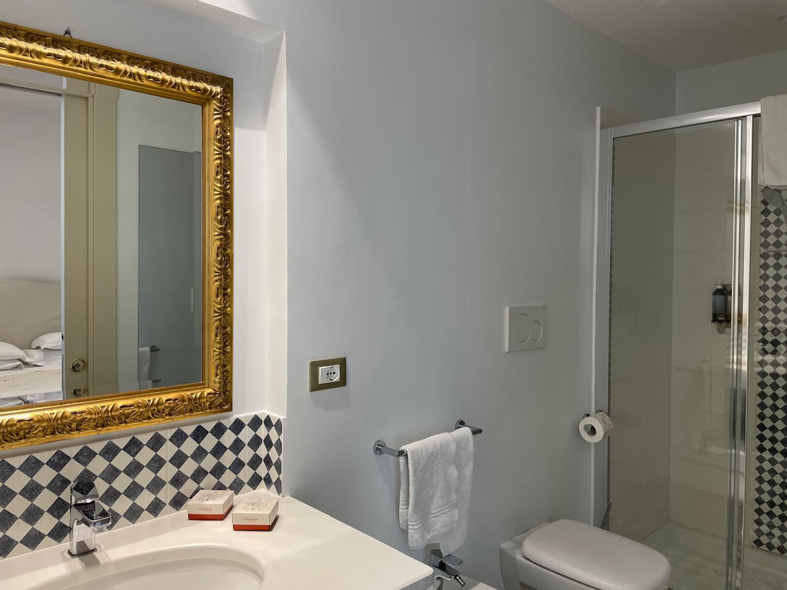 A bathroom with a large mirror, a sink, a toilet, and a shower.