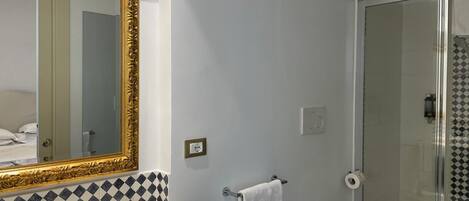 A bathroom with a large mirror, a sink, a toilet, and a shower.