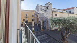 A courtyard with a historic building, a tree, and a gate. - Residenza Il Campanile (Sorrento)