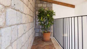 A potted plant on a tiled floor next to a brick wall with a wooden beam ceiling and a black railing. - Residenza Il Campanile (Sorrento)