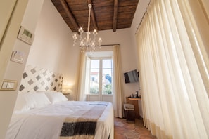 Una camera da letto con un letto, un lampadario, una TV e una finestra con tende.