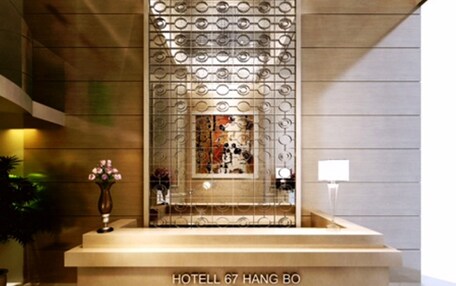 A modern reception desk with a chandelier above, a decorative screen, and a vase with flowers.