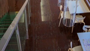 Ein modernes Interieur mit Glastrennwand, einer weißen Rezeption und einer Sitzecke mit Tischen und Stühlen.