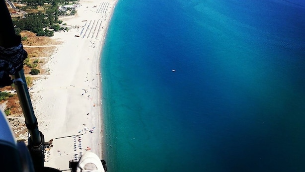 Luftaufnahme einer Küstenregion mit einem langen Sandstrand und einem klaren, blauen Meer.