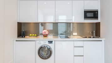 Une cuisine compacte équipée d’un lave-linge, d’une machine à café et d’un four à micro-ondes.