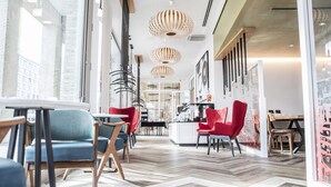 A modern interior with a herringbone floor pattern, red and blue seating, and pendant lighting. - Capri by Fraser Berlin (Berlin)