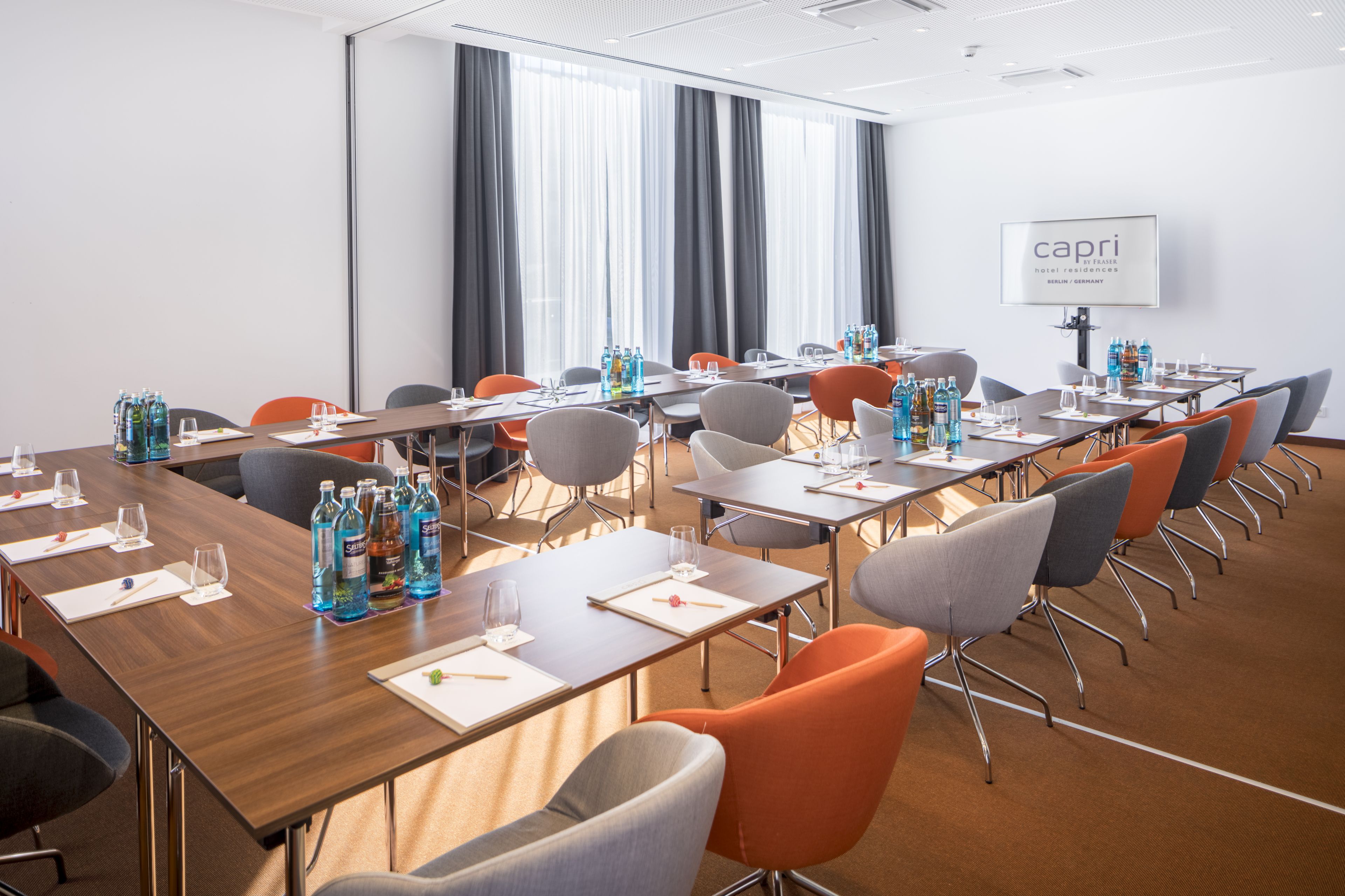 A conference room with multiple tables, chairs, and water bottles.