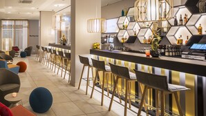 A modern bar area with high stools, a bar counter, and a variety of bottles and glasses. - Capri by Fraser Berlin (Berlin)