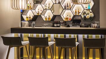 A bar area with a hexagonal wall design, bar stools, and hanging pendant lights.