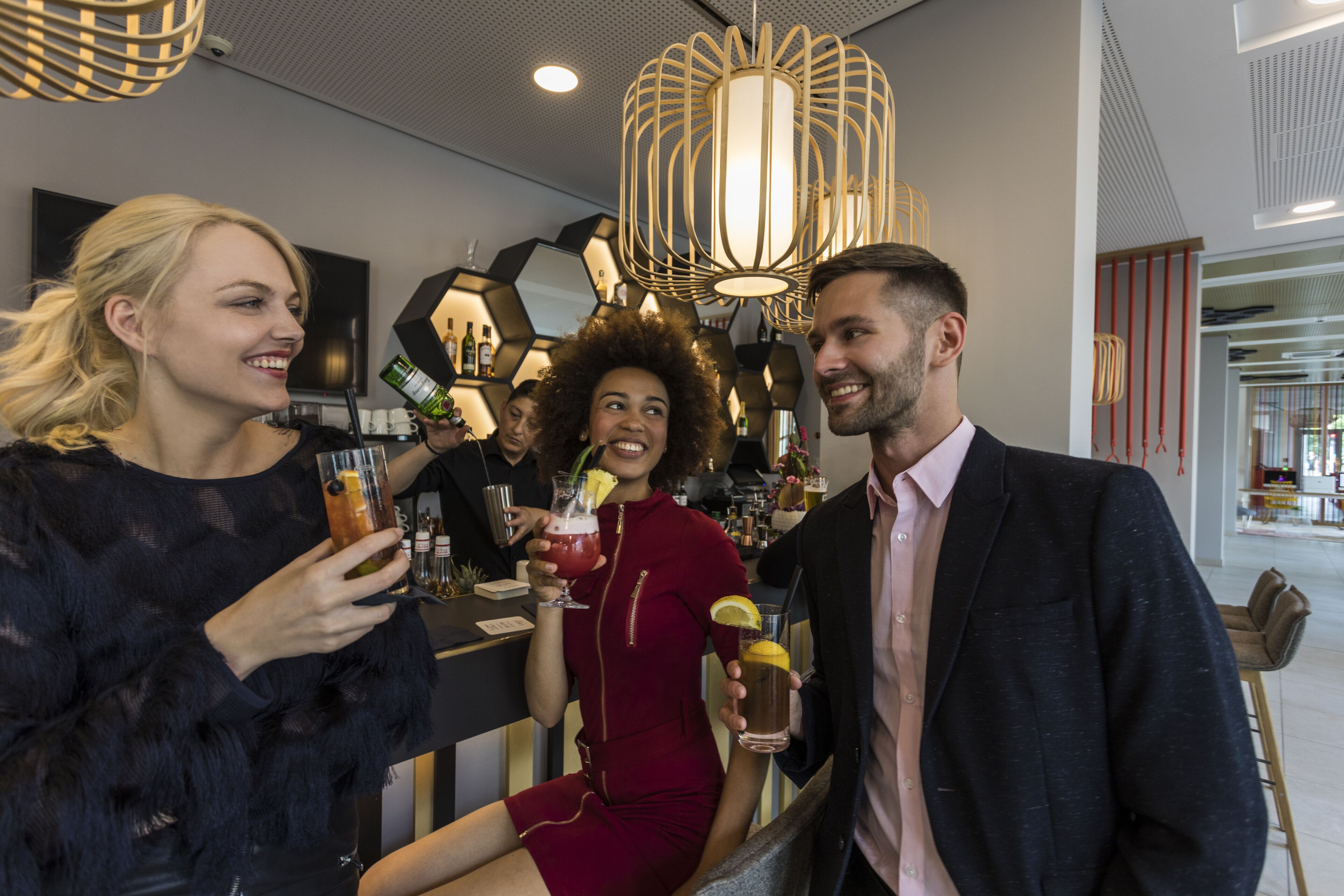 A group of people at a bar with modern decor, including geometric wall patterns and stylish lighting fixtures.