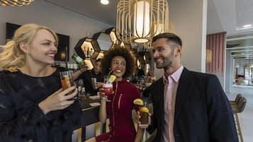 A group of people at a bar with modern decor, including geometric wall patterns and stylish lighting fixtures.