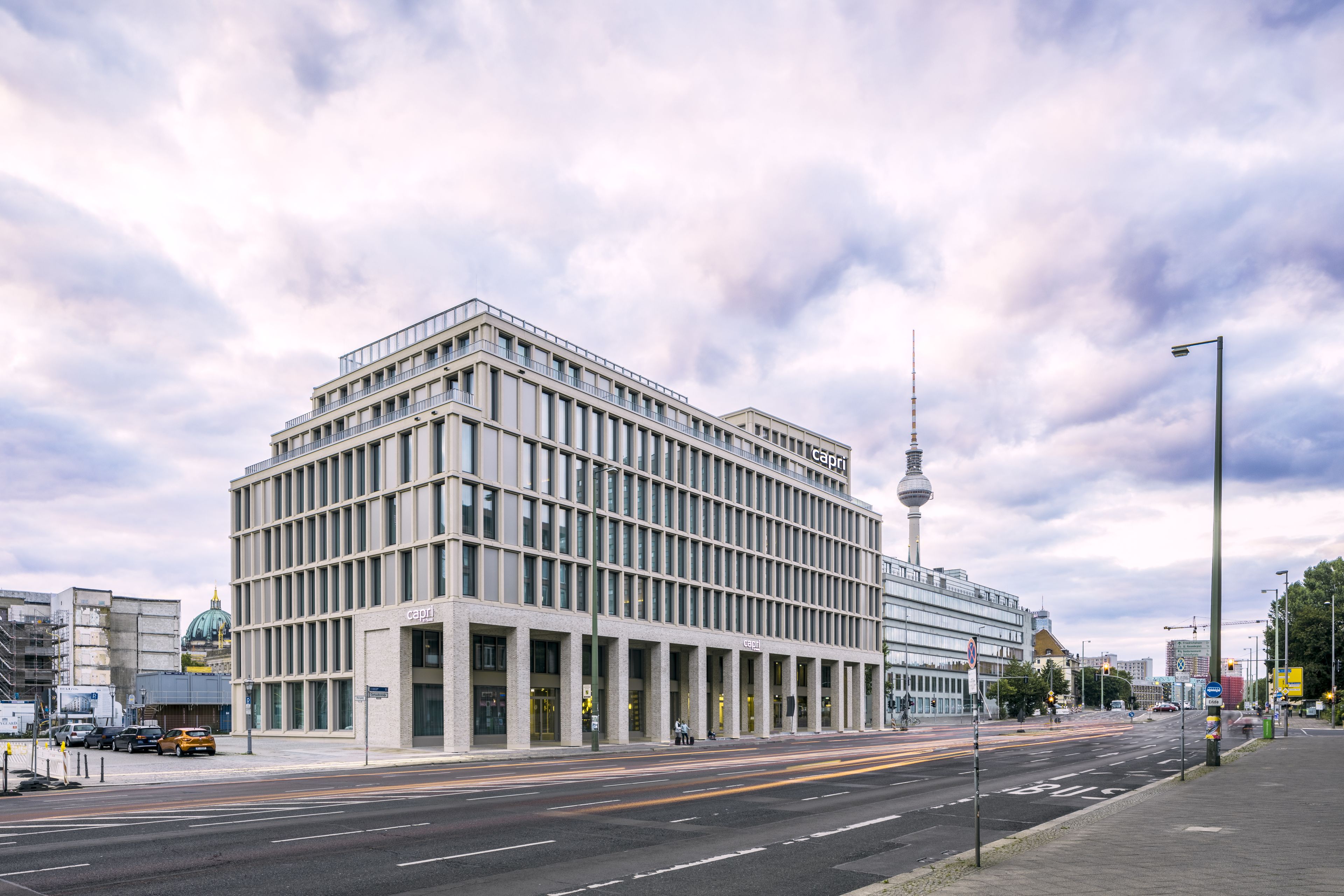 A modern building with a grid of windows and a prominent tower in the background.