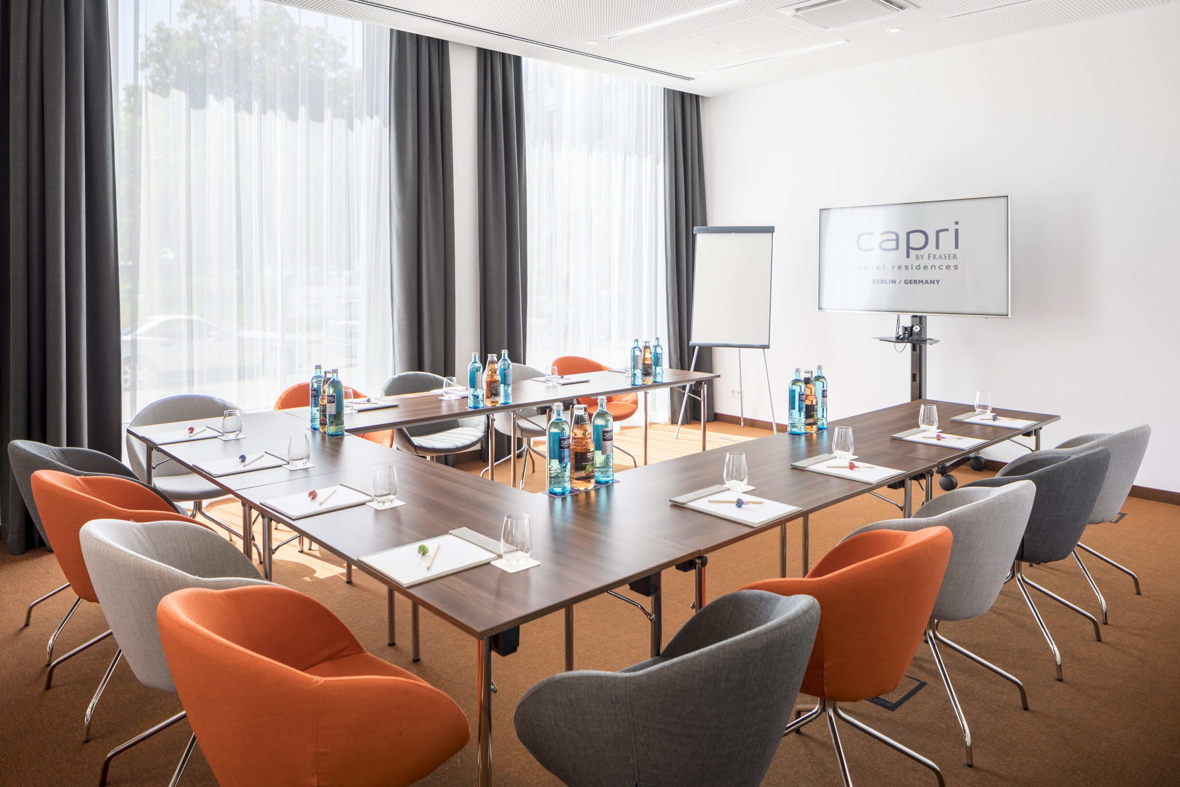 A conference room with a long table, multiple chairs, water bottles, and a whiteboard.