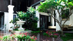 A courtyard with a fountain, lush greenery, and a seating area with a sofa. - Rachamankha Thai Villa (Chiang Mai)