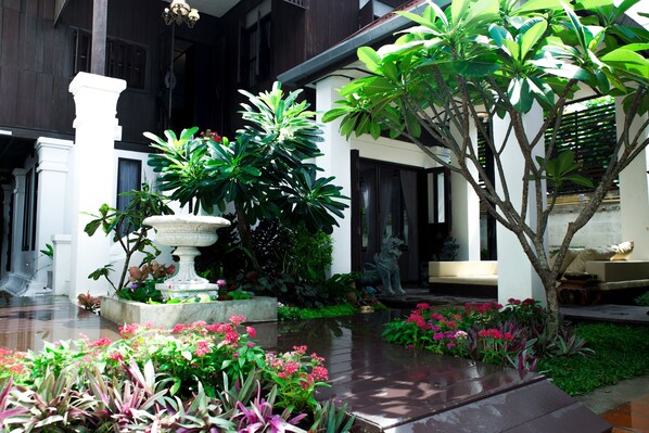 A courtyard with a fountain, lush greenery, and a seating area with a sofa. - Rachamankha Thai Villa (Chiang Mai)