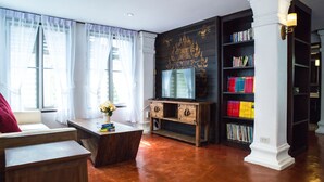 A living room with a wooden coffee table, a sofa, a television, and a bookshelf. - Rachamankha Thai Villa (Chiang Mai)