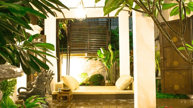 A well-maintained garden with a seating area, a decorative metal sculpture, and a water feature. - Rachamankha Thai Villa (Chiang Mai)