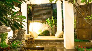 Un jardin bien entretenu, agrémenté d’un espace aménagé pour s’asseoir, d’une sculpture métallique décorative et d’un élément aquatique.