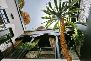 Un interior de varios niveles con una escalera central, barandas de metal y plantas en macetas.
