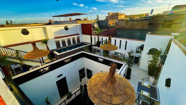 Una terraza en la azotea con piscina, mobiliario exterior y vistas a edificios históricos.
