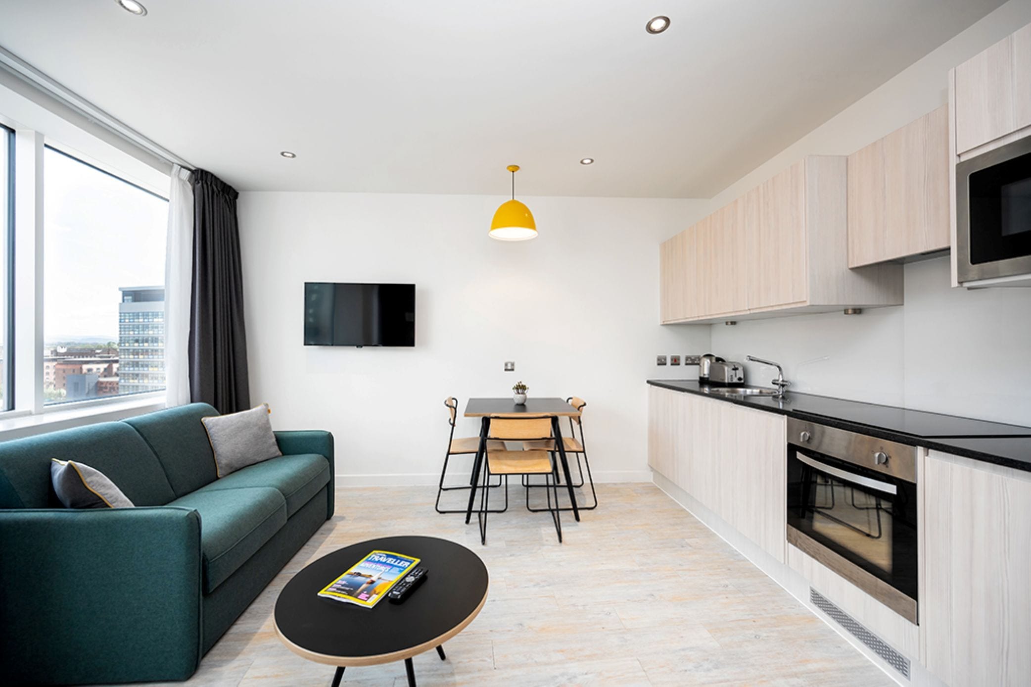 A modern living space with a sofa, coffee table, dining table, and kitchen area.