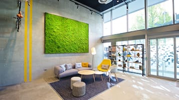 Un interior moderno con una pared verde, zona de estar y exhibición de zapatos.