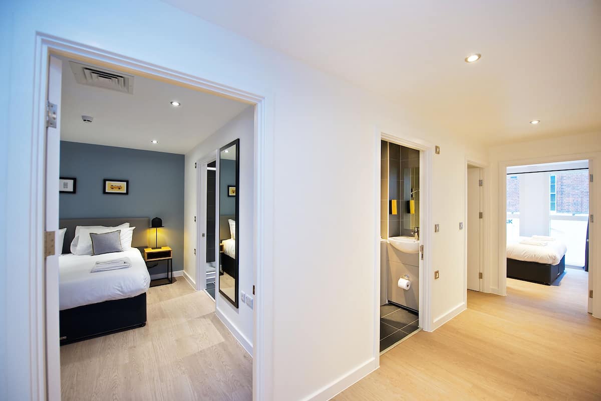 A modern hotel room with a bed, bedside table, and a bathroom with a toilet and sink.