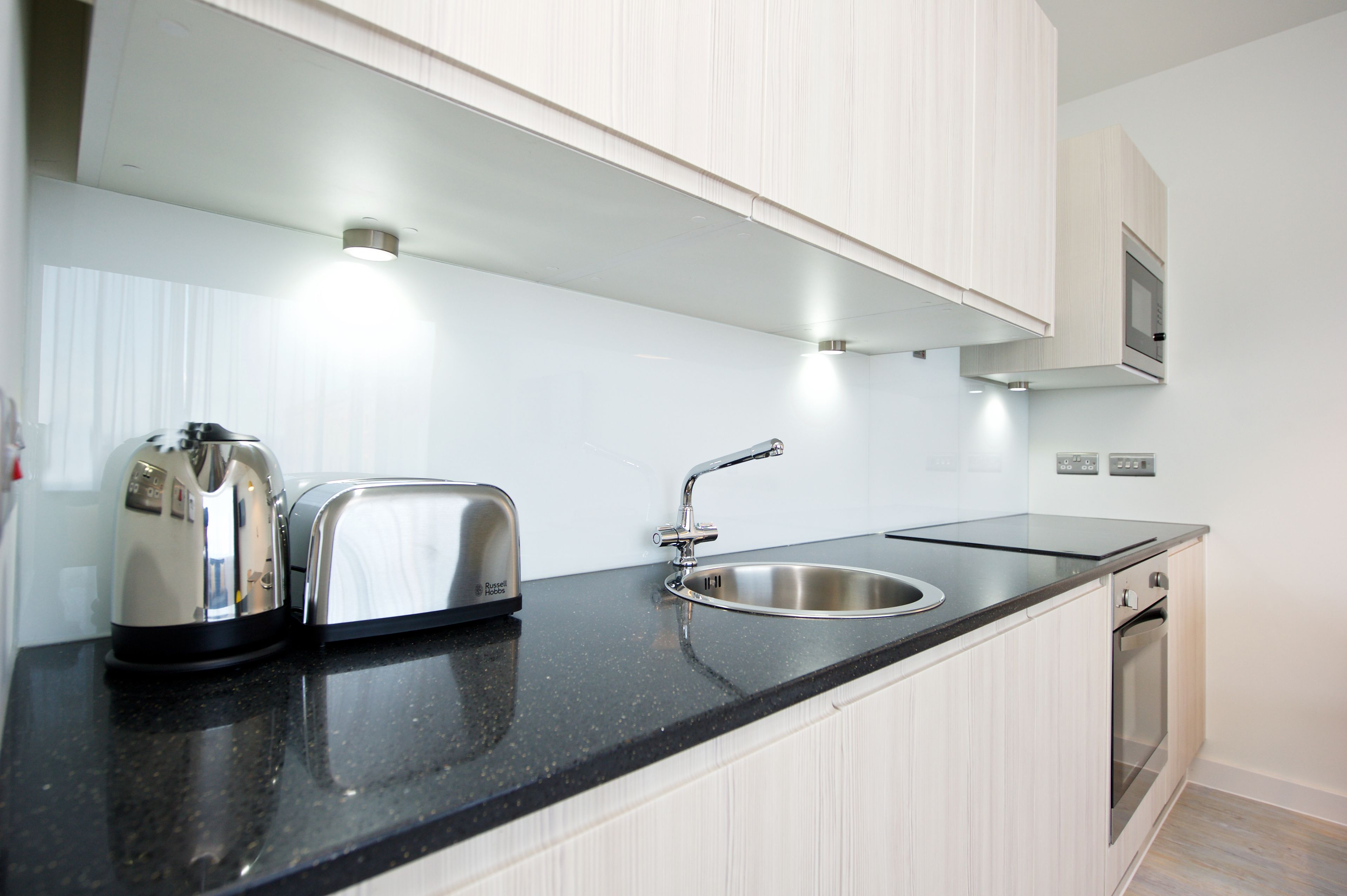 A modern kitchen with a black countertop, stainless steel appliances, and a built-in oven.