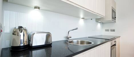 A modern kitchen with a black countertop, stainless steel appliances, and a built-in oven.