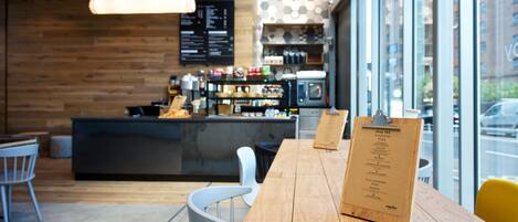 A cafe interior with a wooden table, chairs, a menu board, and a coffee machine.