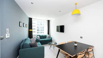 Un salon moderne avec un canapé, une table à manger et un téléviseur fixé au mur.