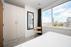 A modern hotel room with a large window, a wooden wardrobe, a chair, and a bed. - Staycity Aparthotels, Manchester, Piccadilly (Manchester)