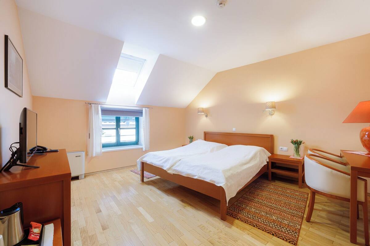 Une chambre à coucher comprenant un lit, un bureau, une chaise, une fenêtre et un luminaire au plafond.