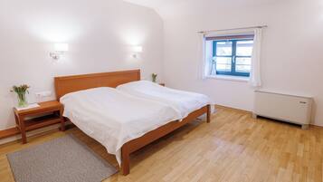 A bedroom with a wooden bed, bedside tables, a window with curtains, and a radiator.