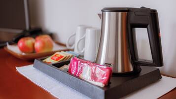 A breakfast tray with a kettle, a mug, and packaged food items on a table.