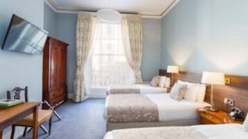 A hotel room with two beds, a desk, a chair, a wardrobe, and a television on the wall.