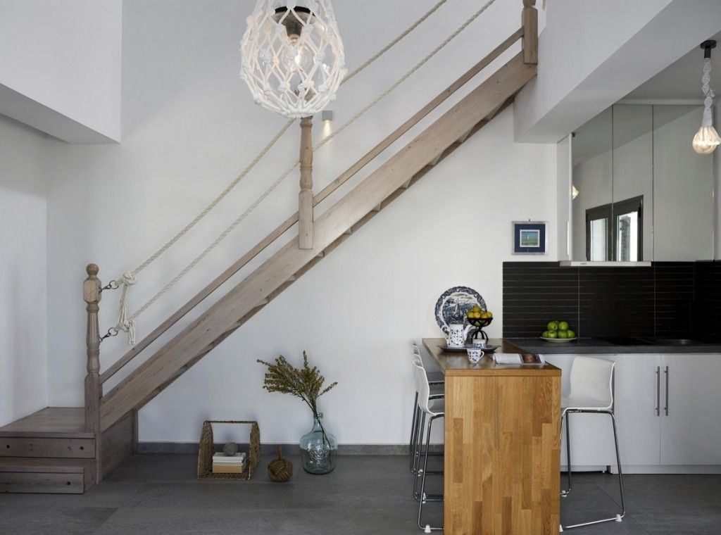Eine moderne Küche mit einer Holztreppe, weißen Schränken und einem Essbereich mit Holztisch und -stühlen.