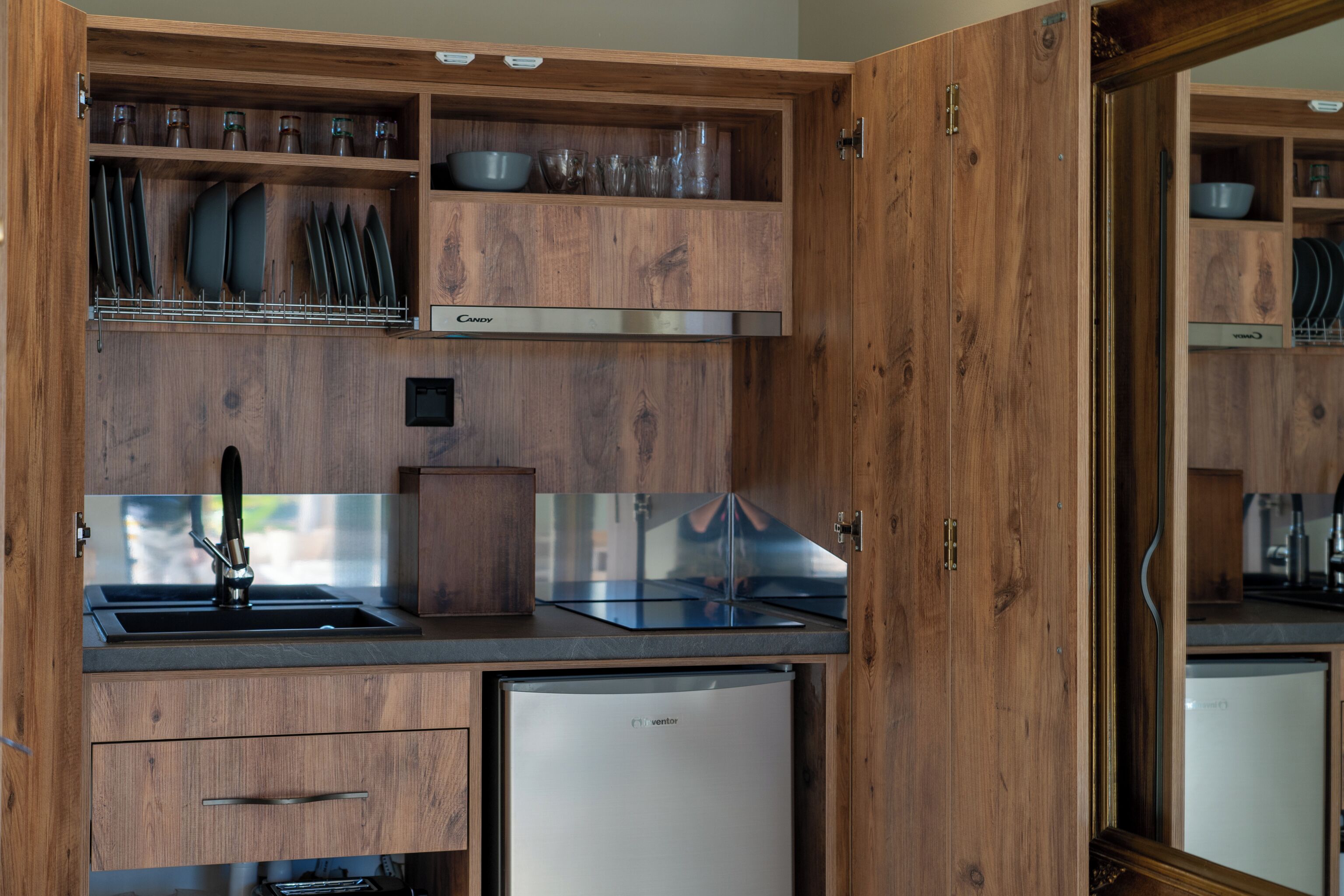 A compact kitchen with wooden cabinetry, a stainless steel sink, and a built-in refrigerator.