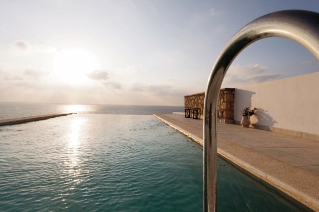 A pool with a clear view of the sea and a sunset.