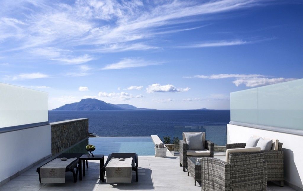 Une terrasse sur le toit offrant une vue sur la mer et les montagnes, aménagée avec des sièges d’extérieur et une petite table.