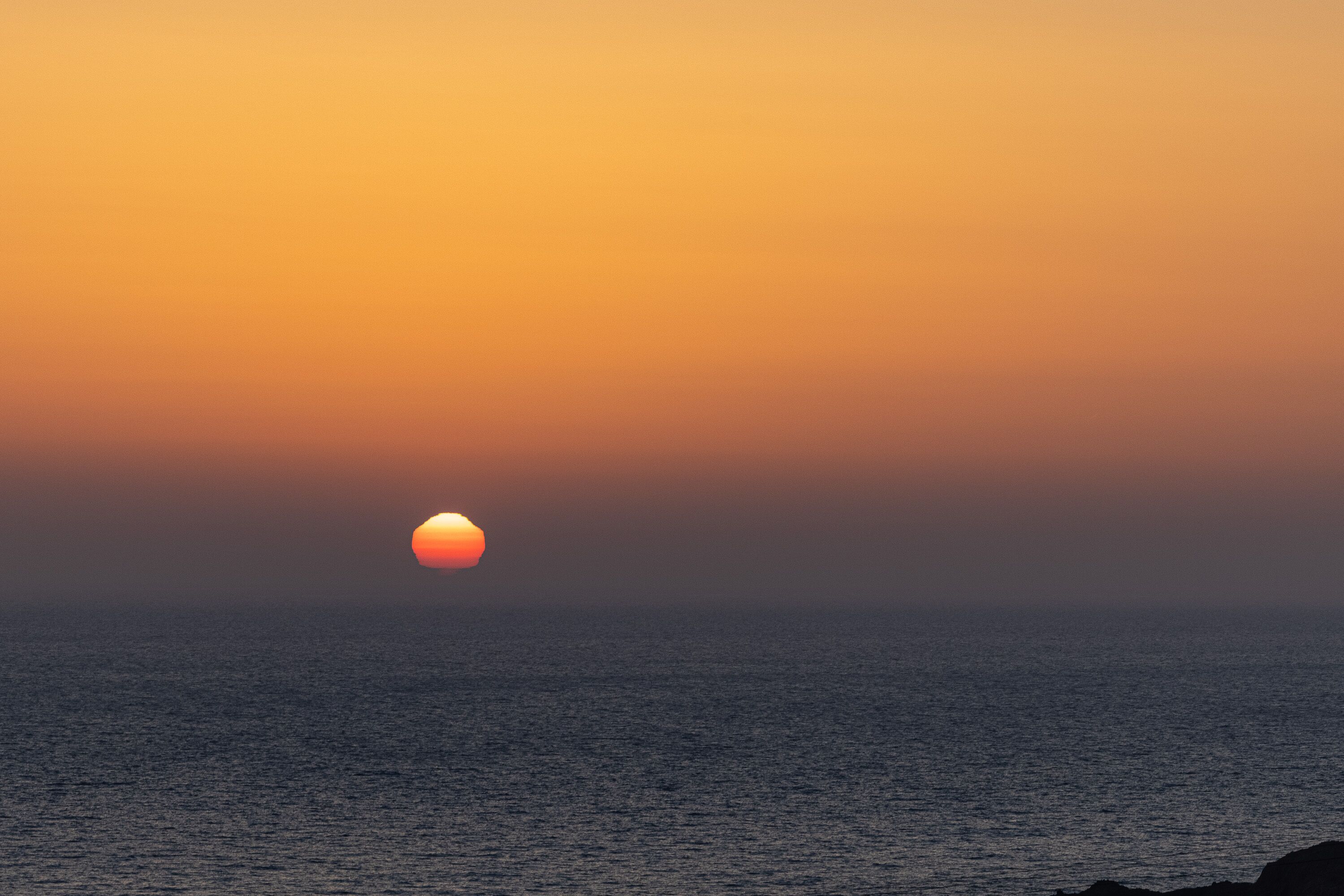 A sunset over the ocean with a clear horizon.