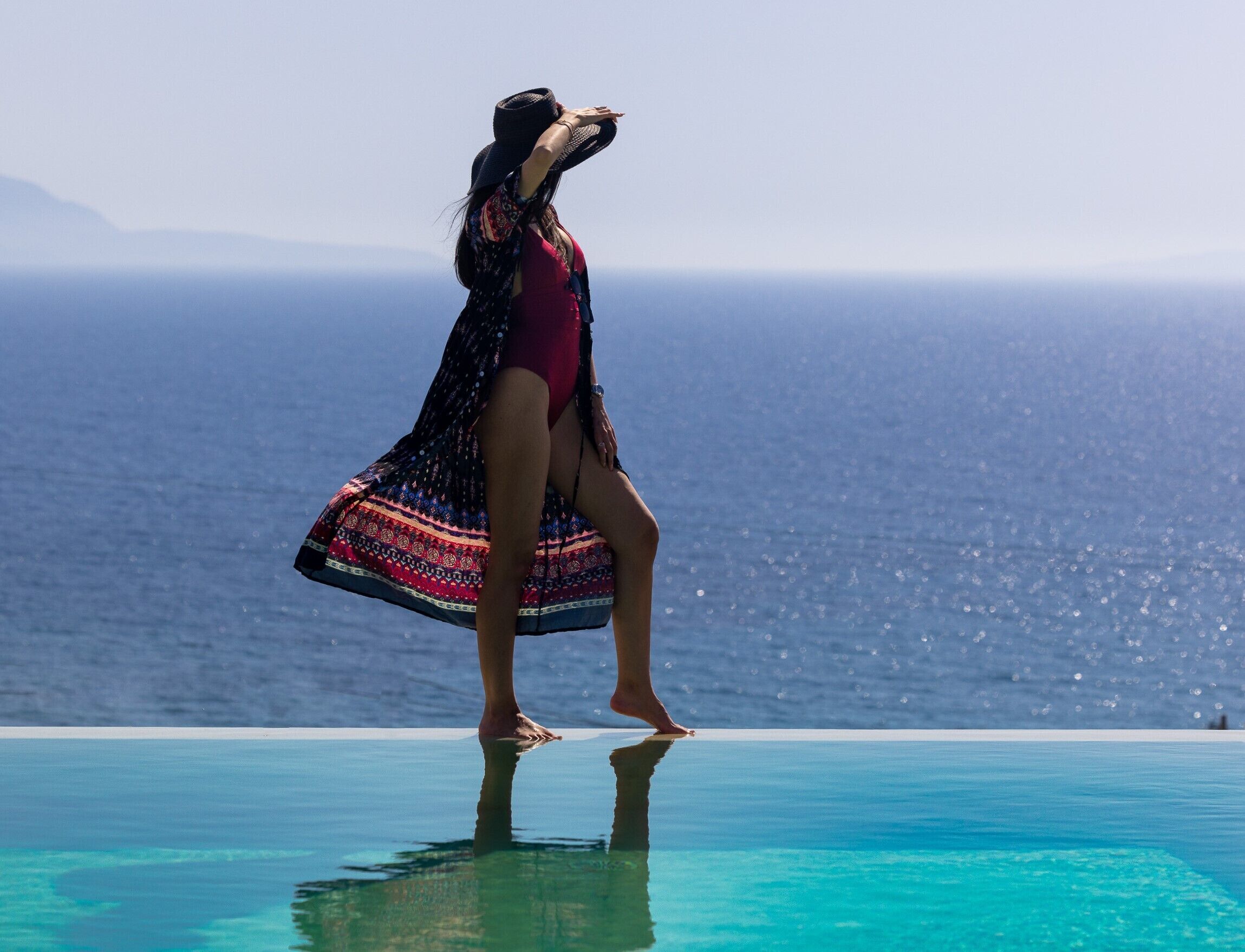 A person standing on a pool edge with a view of the ocean.