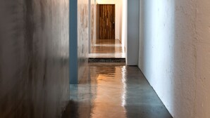 Un corridoio stretto e poco illuminato con una porta di legno in fondo.